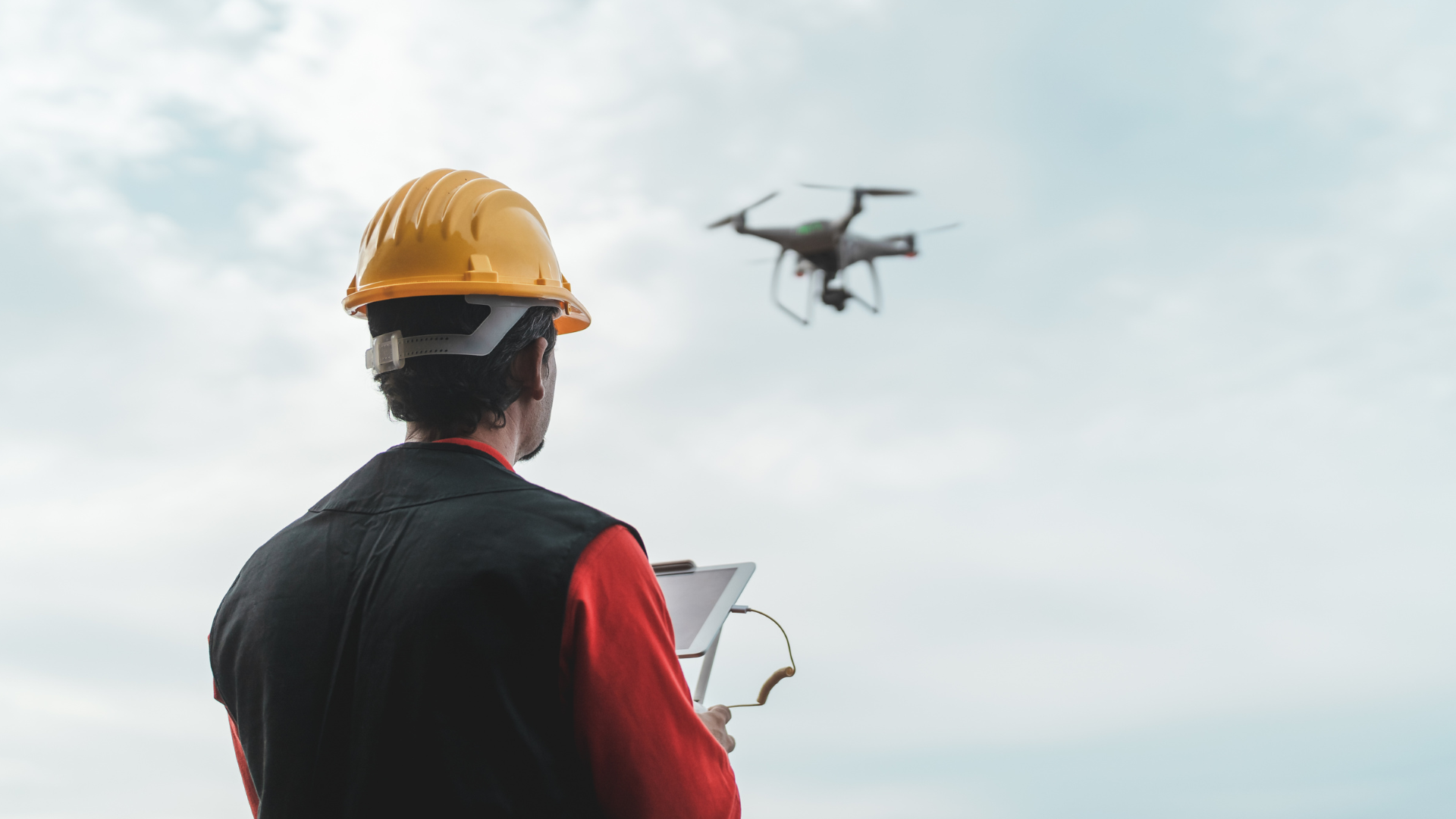 A construction worker flying a drone