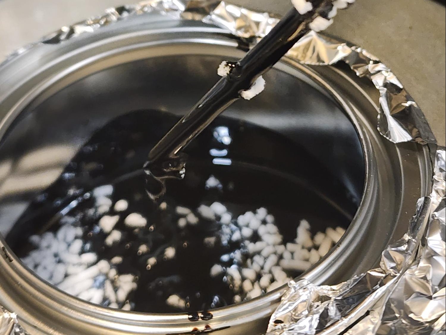 Asphalt binder in a shear mixer with a researcher adding polymer to it