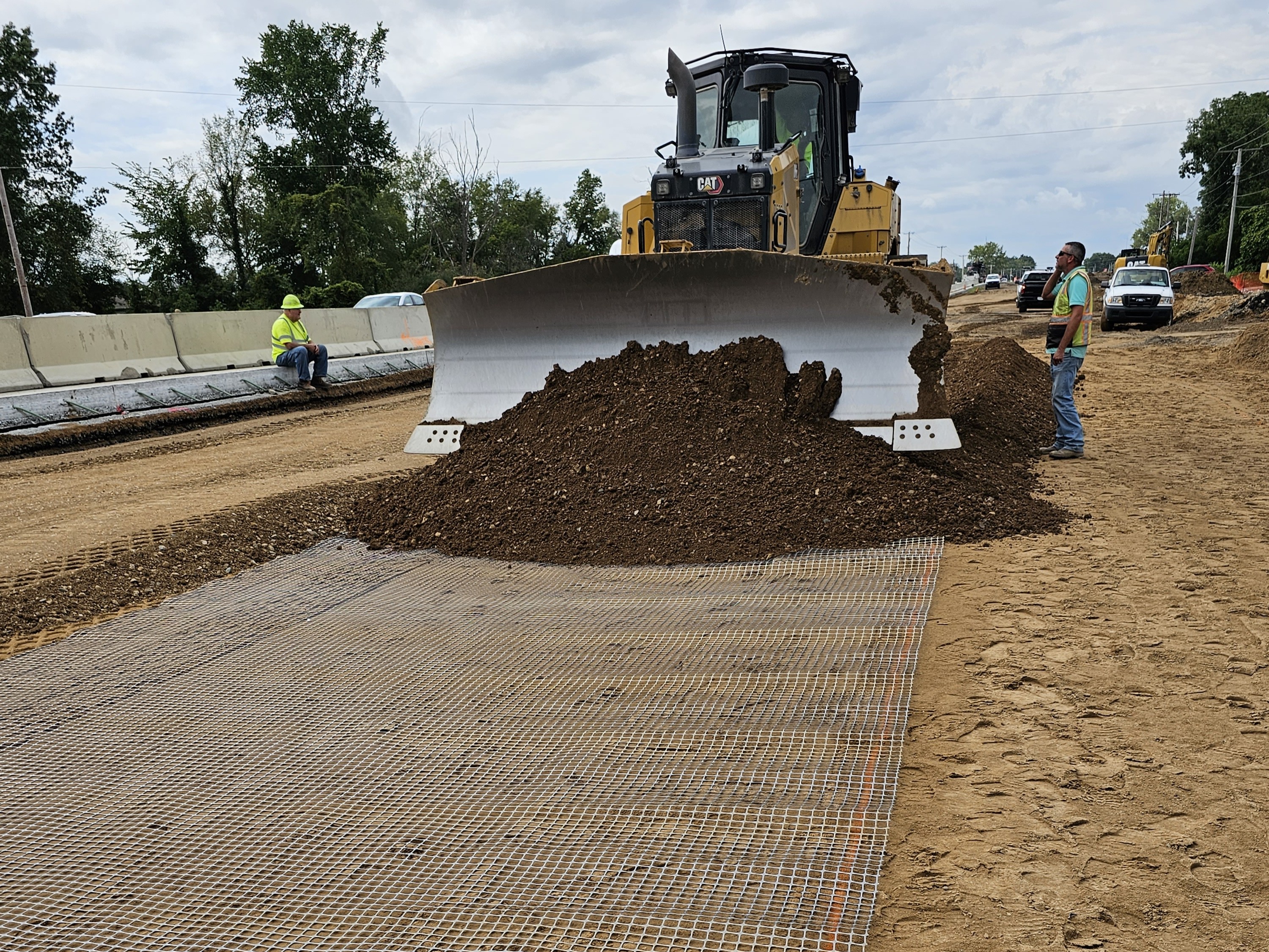 Construction workers paving over a road with geosynthetics on it.