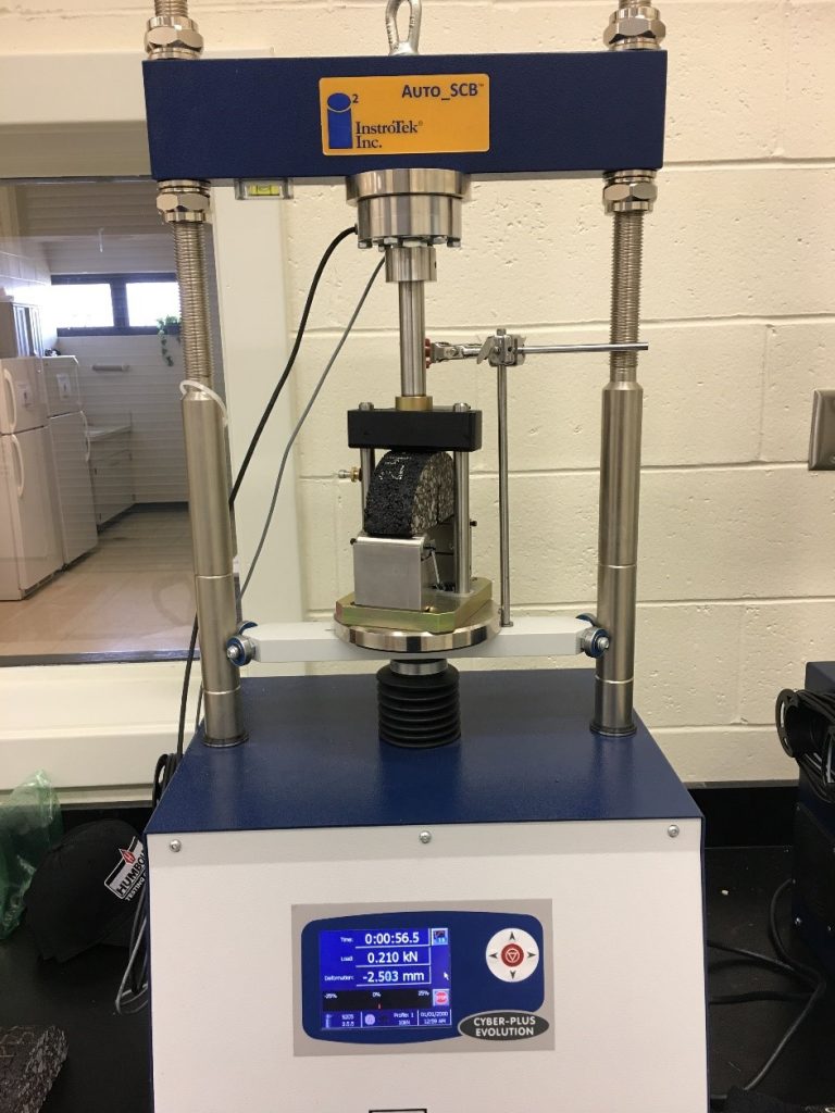 The I-FIT Instrotek apparatus with an asphalt sample.