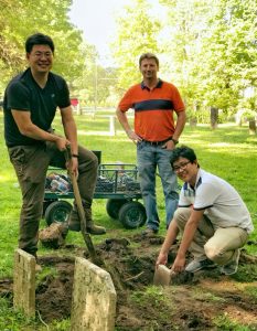 Doctoral student Siqi Wang, left, ICT engineer Michael Johnson, center, and doctoral student Shan Zhao unearth a buried gravestone.