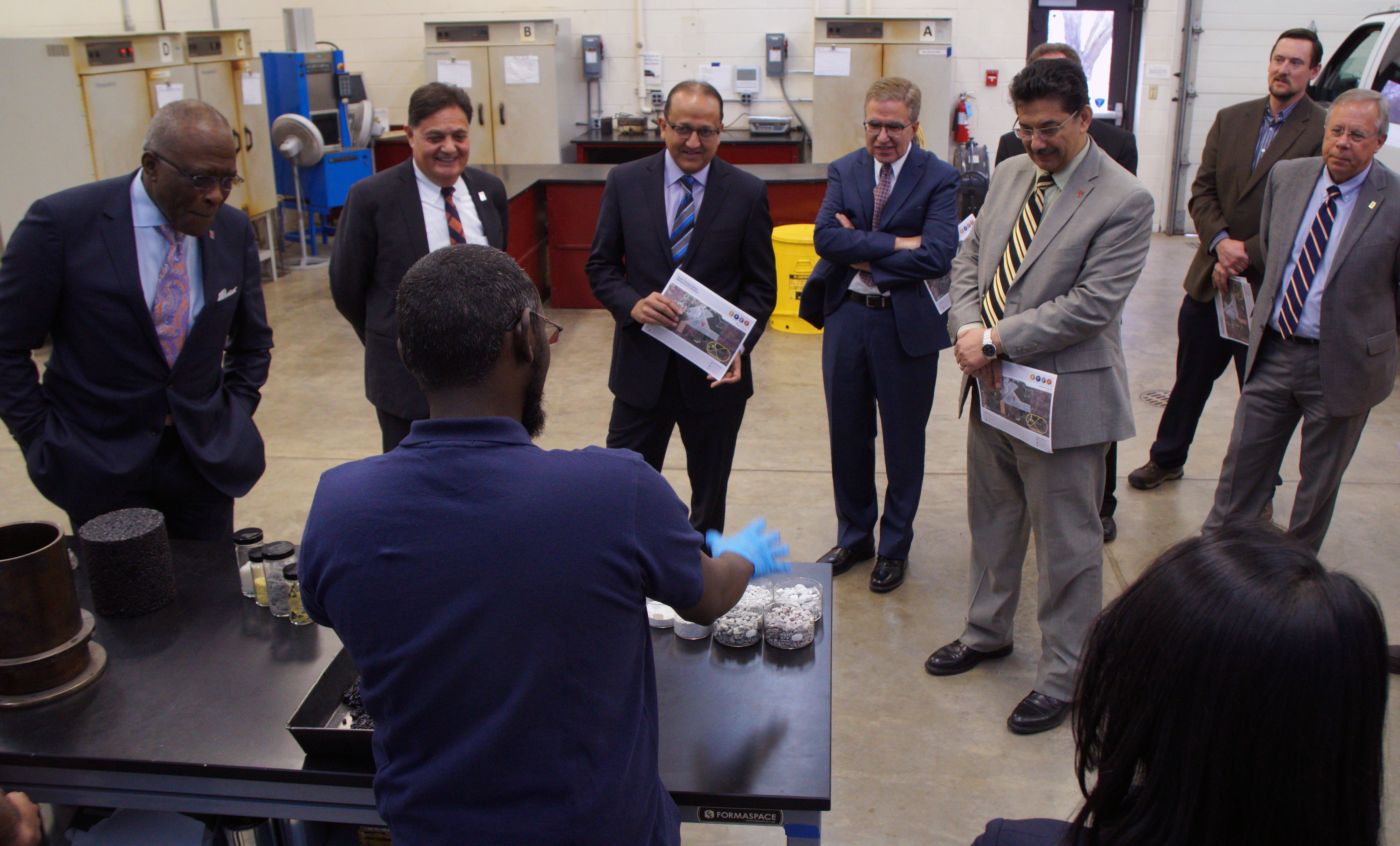 Uthman Mohamed Ali shows visitors several constituent materials that make up asphalt concrete.