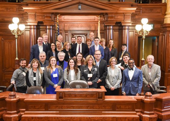 Champaign County First initiative members were all smiles posing for a photo with Sen. Chapin Rose (R-Mahomet) in the Senate chamber of the Illinois State Capitol building earlier in March.