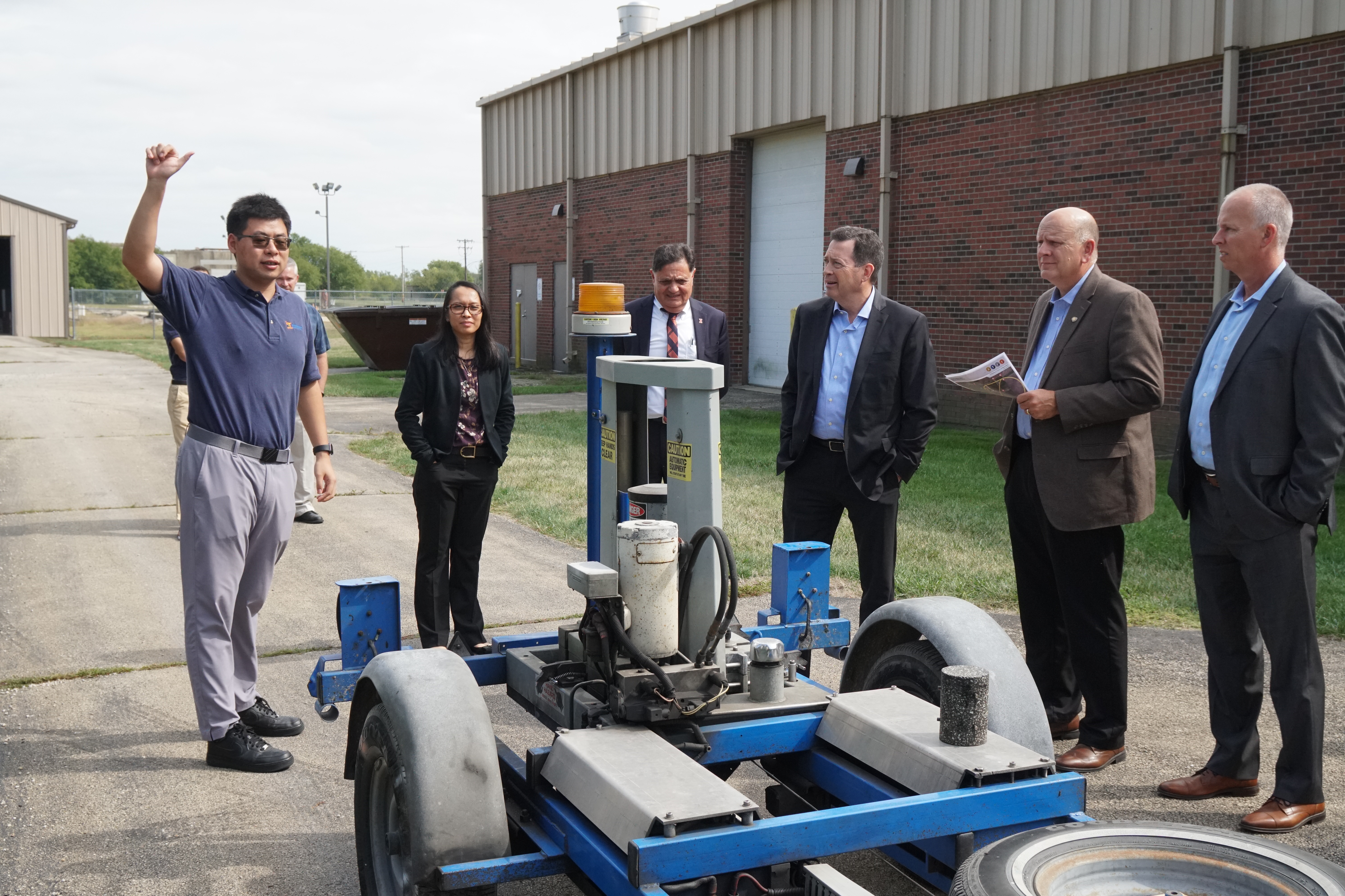 UIUC doctoral student Siqi Wang, left, shows John Deere personnel ICT&rsquo;s&nbsp;falling weight deflectometer at its research facility in Rantoul on Sept. 25.