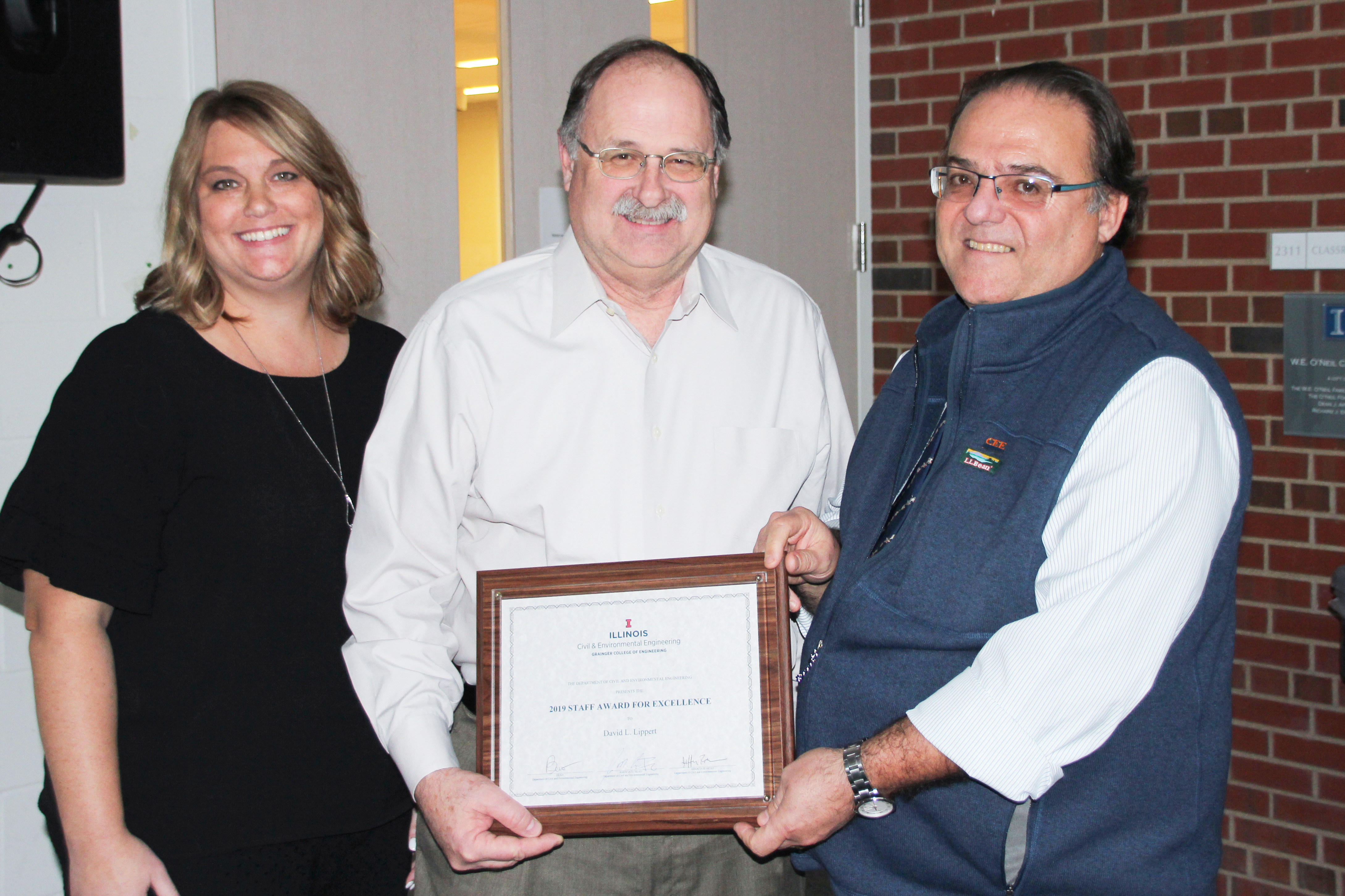 David Lippert, middle, ICT&rsquo;s senior sustainability implementation engineer, was all smiles earlier on Nov. 18, 2019, when awarded the Staff Award for Excellence by Kristi Anderson, left, ICT&rsquo;s senior financial operations manager, and Benito Mari&ntilde;as, CEE&rsquo;s former department head, at the M.T. Geoffrey Yeh Student Center. &ldquo;David is very well respected for his sense of devotion and commitment to his career,&rdquo; said Imad Al-Qadi, ICT&rsquo;s director and UIUC CEE Bliss Professor of Engineering, who took part in nominating Lippert for the award. &ldquo;He is a distinguished engineer due to his high professional standards, ethics and humbleness in working with students, faculty and staff.&rdquo;