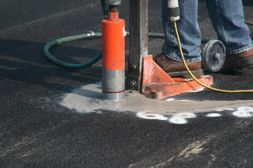 A contractor drills into an asphalt sample to measure its density &mdash; a major factor driving contractor pay disincentives.