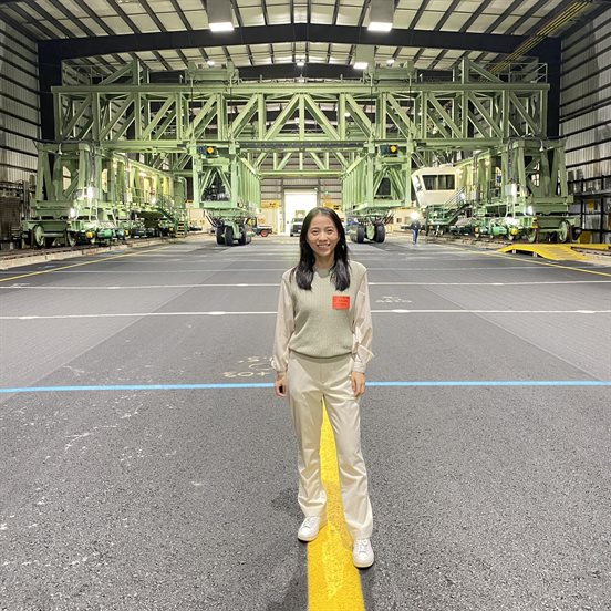 Qingwen Zhou, a University of Illinois Urbana-Champaign Department of Civil and Environmental Engineering doctoral candidate, poses in front of the National Airport Pavement Test Vehicle, a rail-based device capable of simulating aircraft weighing up to 1.3 million pounds, at Federal Aviation Administration&amp;amp;amp;amp;rsquo;s National Airport Pavement Test Facility.