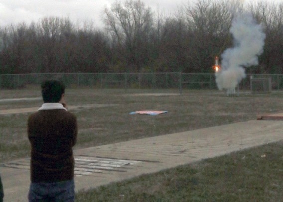 A UIUC team member watches his rocket power on for a soft landing on the grass.