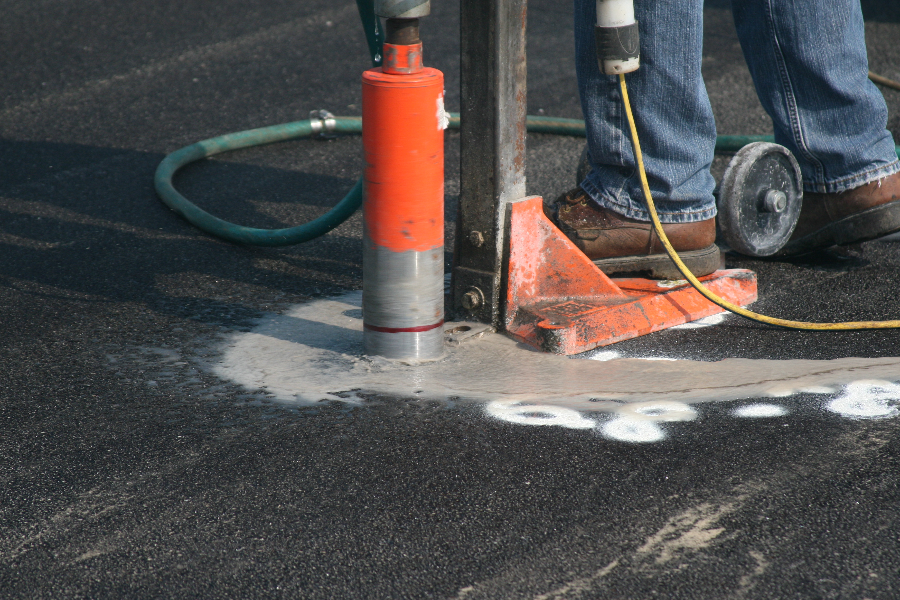 A contractor drills into an asphalt sample to measure its density. IDOT uses three tests to measure the acceptability of hot-mix asphalt: pay for performance, quality control for performance, and quality control and quality assurance.