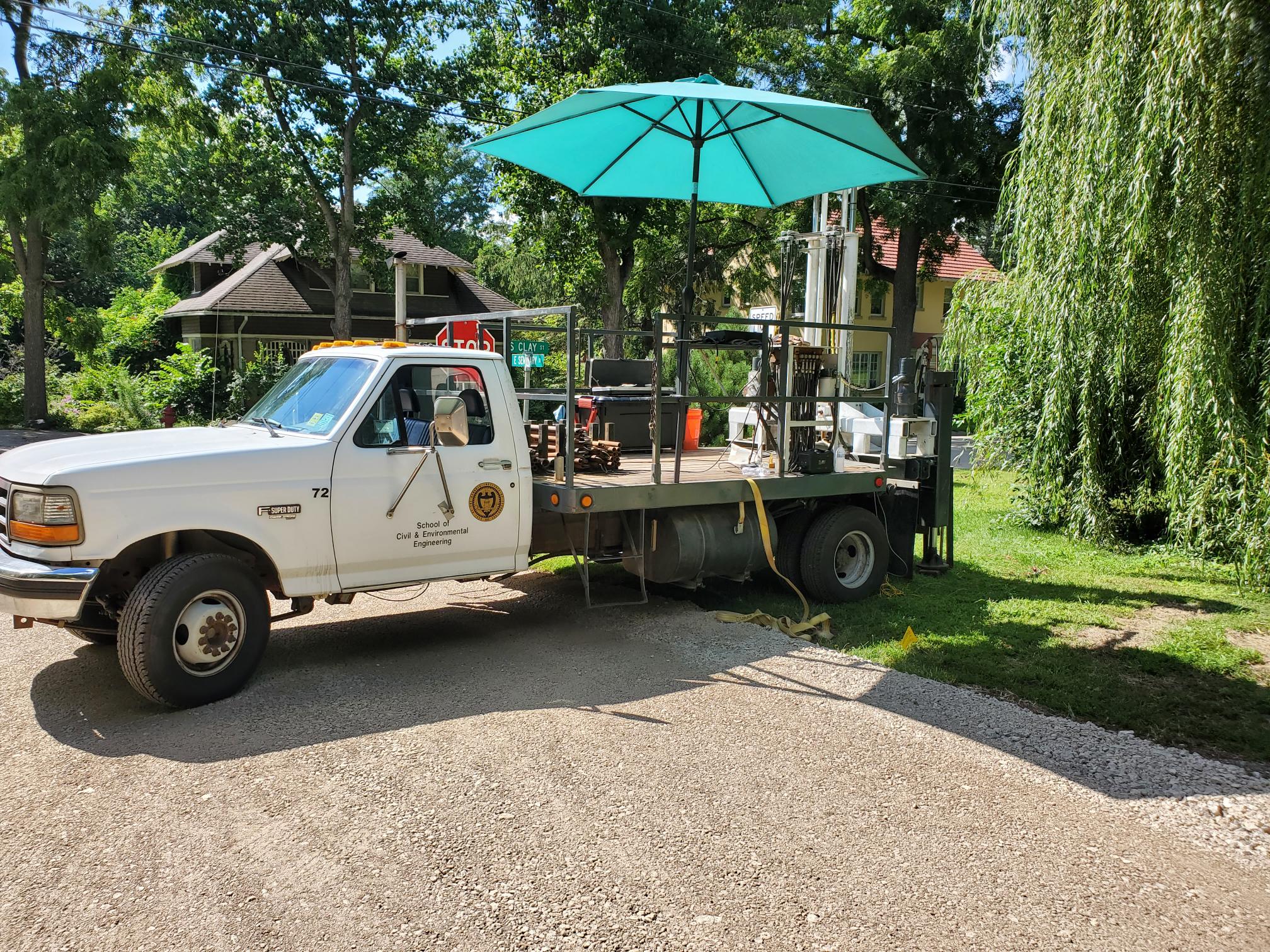 Provided by Cody Arnold. The Georgia Tech cone penetration testing rig while in Mount Carroll, Illinois. The rig consists of a hydraulic pushing mechanism with two ram sets mounted at the rear of a modified truck bed along with anchors and leveling pistons.